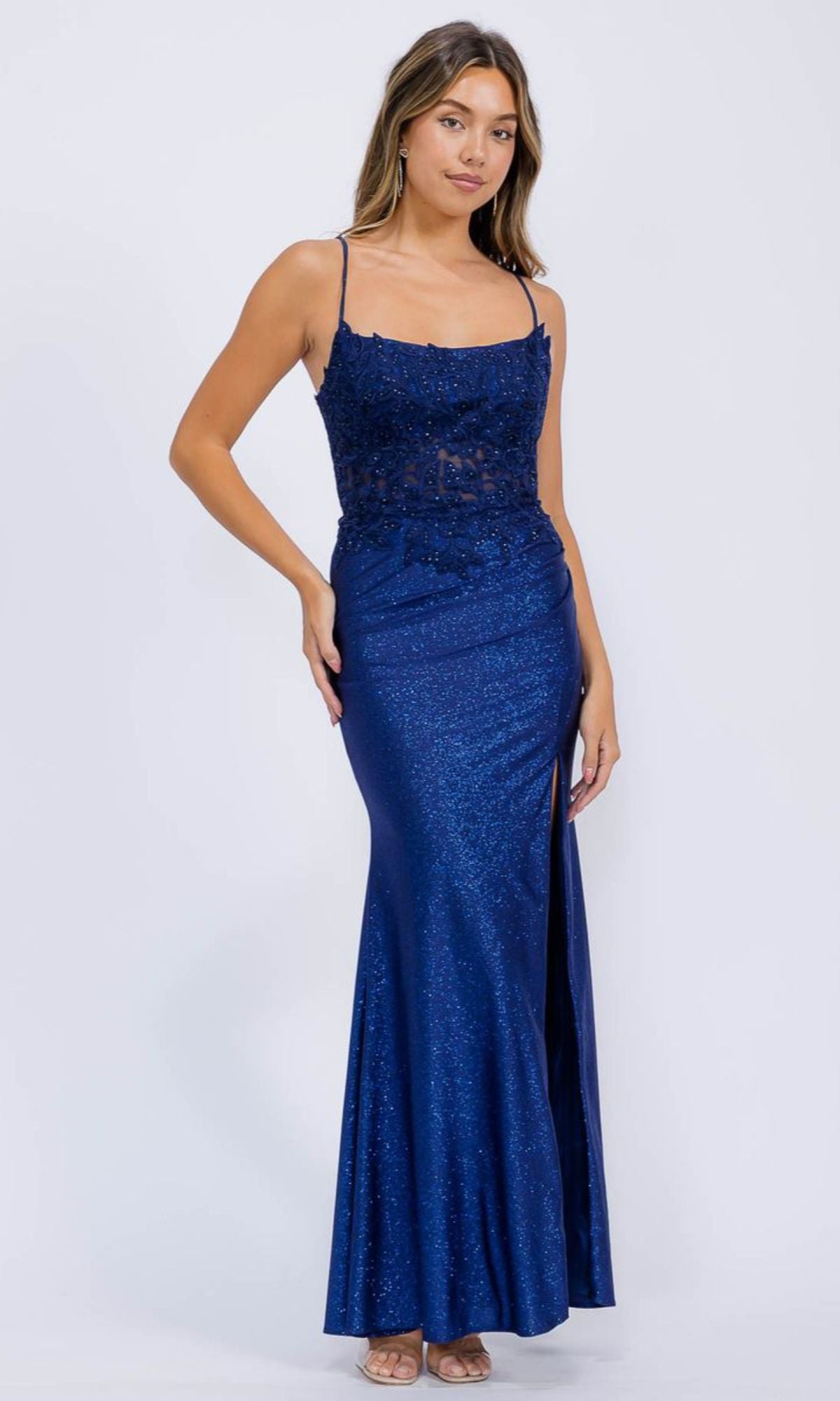 A woman wears the Lace-Corset Long Jersey Prom Dress Eureka EK129, a sleeveless navy blue gown with a corset-style lace bodice and a thigh-high slit.